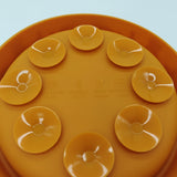 Close-up of an orange silicone suction cup lid with embossed text indicating material and heat resistance, shown against a light blue background.