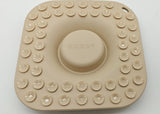 A beige silicone bath mat with a central circular suction cup and a border of smaller suction cups, shown on a plain light background.